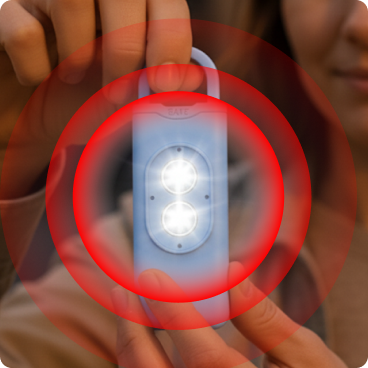 A woman holding HerAlarm with illuminated LEDs and an illustrative sound-wave graphic